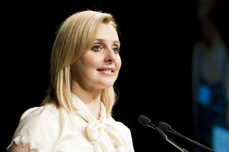 a blonde woman speaking at a microphone