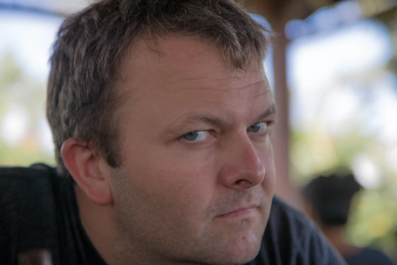 an older man looks towards the camera in close up