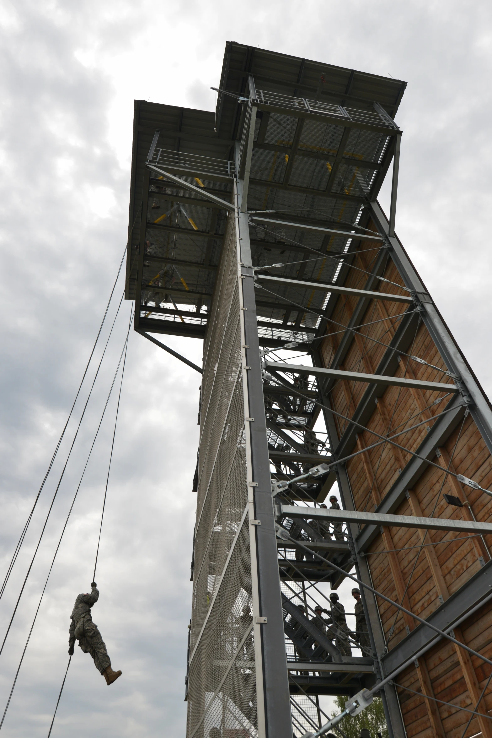 a man hangs from ropes while climbing a tall structure