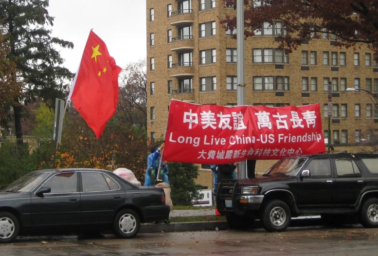 an asian - american protester holds up a red banner