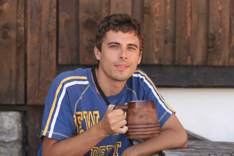 a man sitting on a bench holding a brown cup