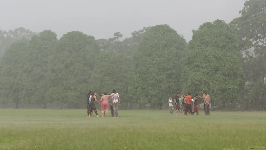 a group of people walking across a field in the rain