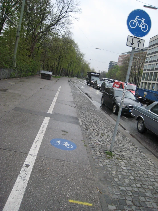 the street has cars on it and many trees line the sides