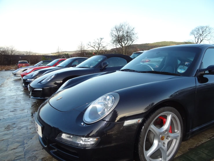 several black porsches parked on a rainy day