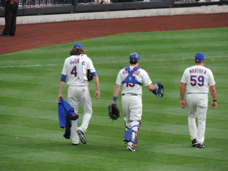 three baseball players walking off the field
