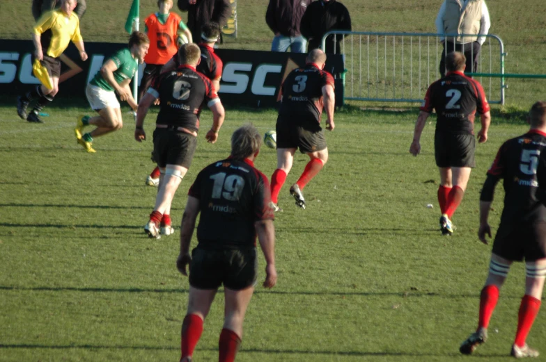 players in black and red running on field