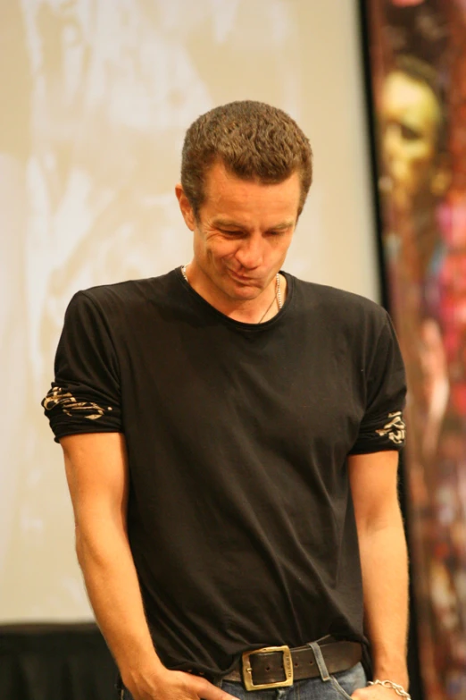 a man wearing a black shirt while looking down at his cellphone