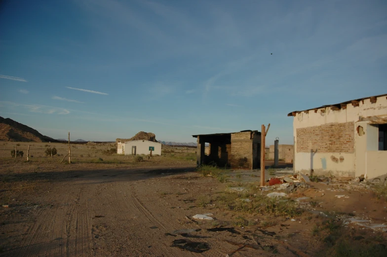 two abandoned buildings in an open country field