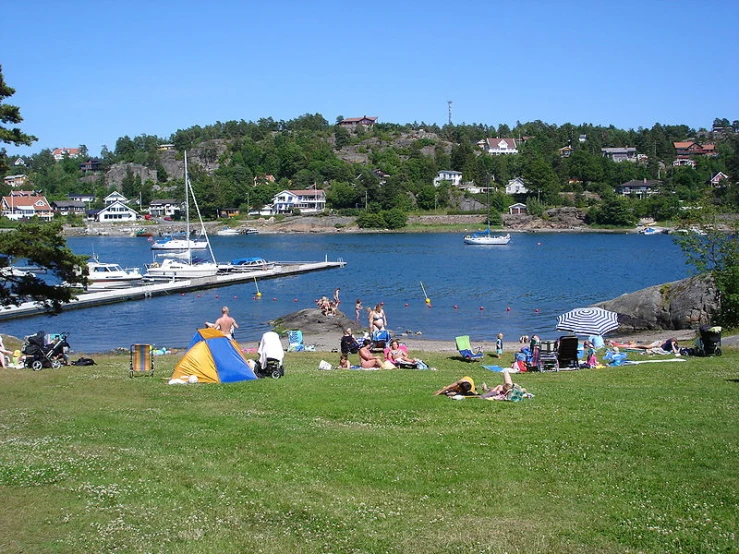 a small group of people sit in the sun at the water's edge