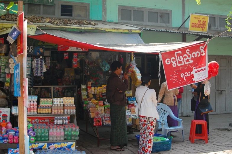 many people are standing outside a store selling some items