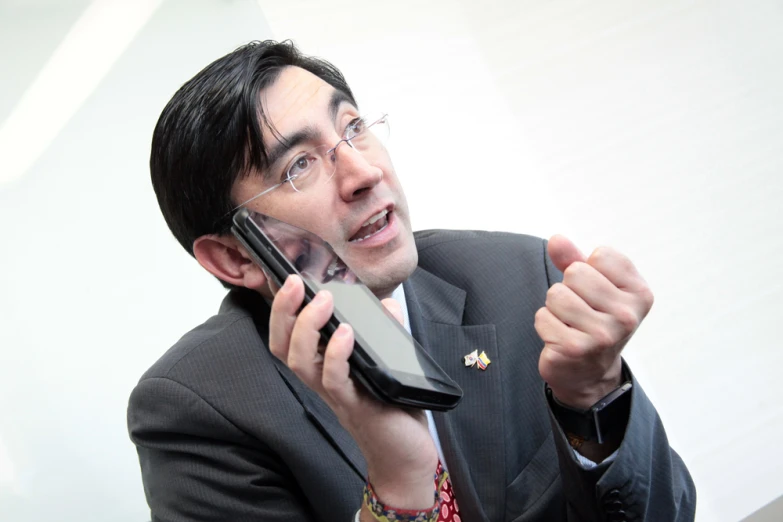 a man in a suit holding a cell phone up to his face