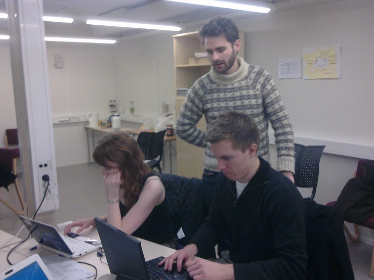 a man with a beard, seated in front of two laptops