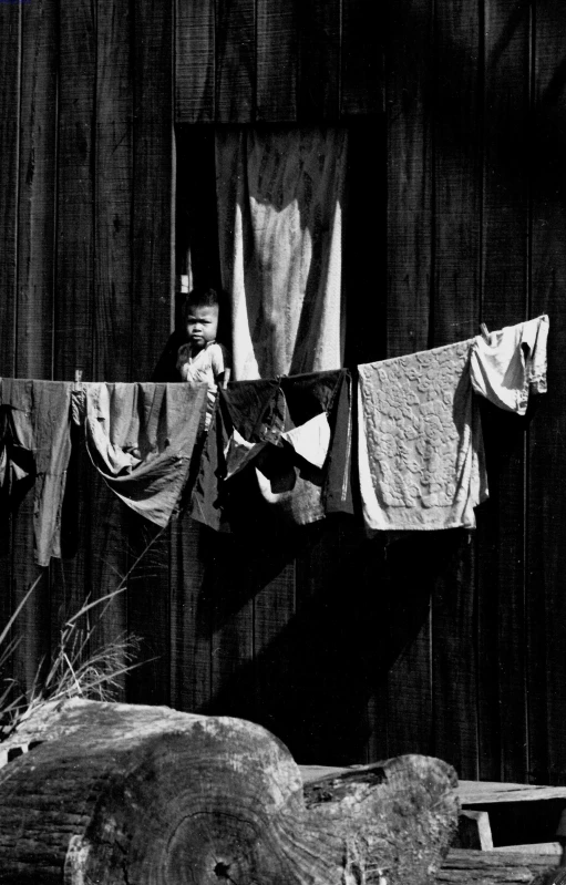 clothes hanging outside a wooden house with an animal on the ground