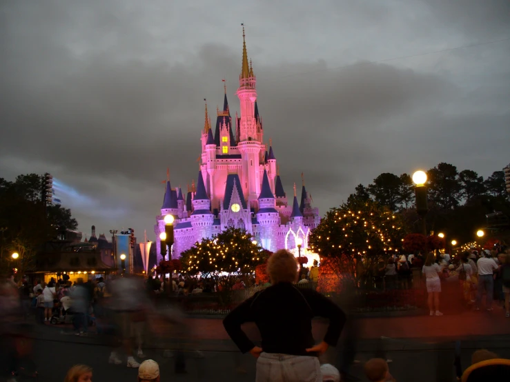 a pink castle at night is lit up with many lights