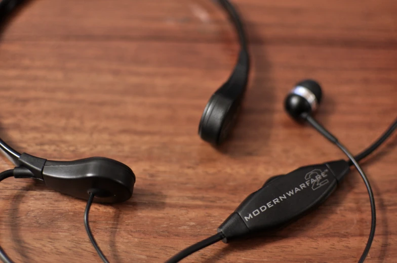 the black cord of a pair of headphones resting on a wood surface