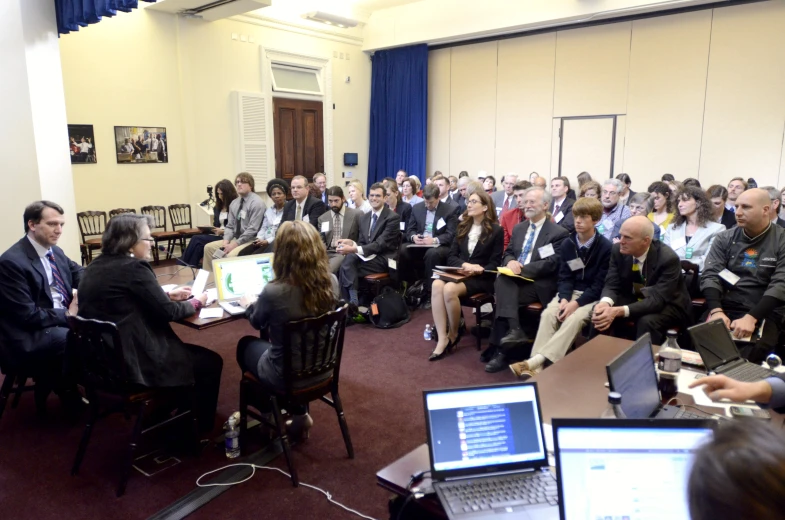 group of people sitting in chairs with laptops and talking to them