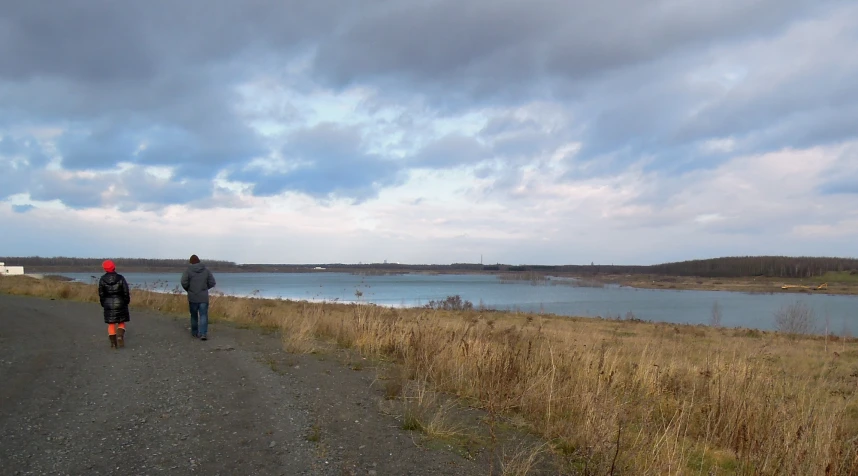 two people walk down the road on a cloudy day