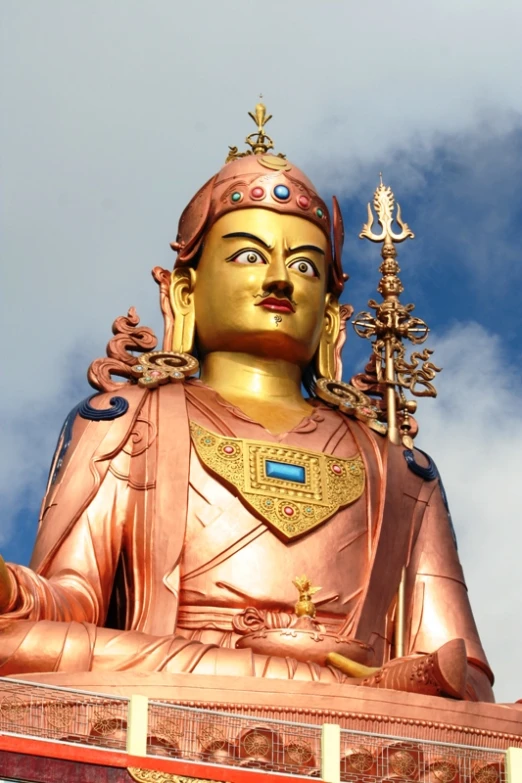 the golden buddha statue is sitting under a blue sky