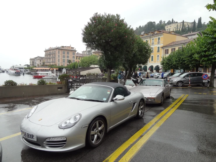 two silver sports cars parked on a wet street