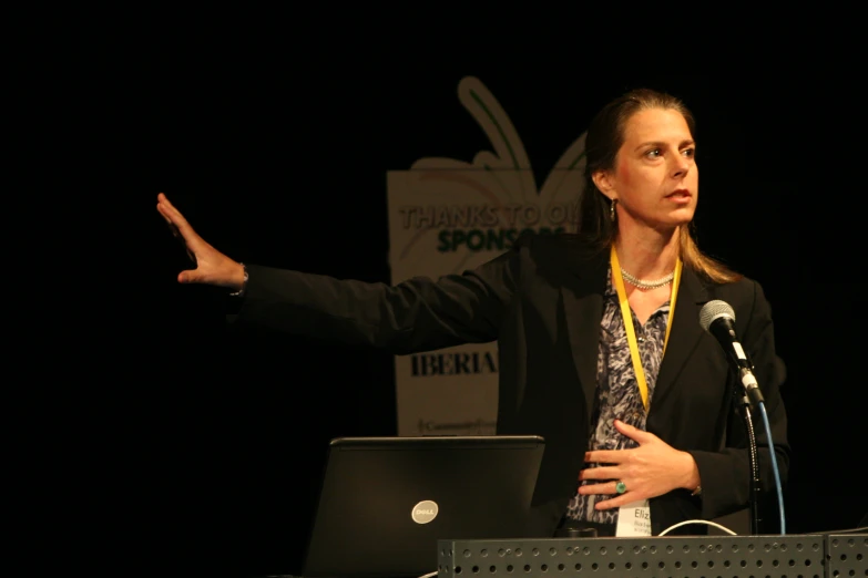 the woman is presenting at the event with her laptop