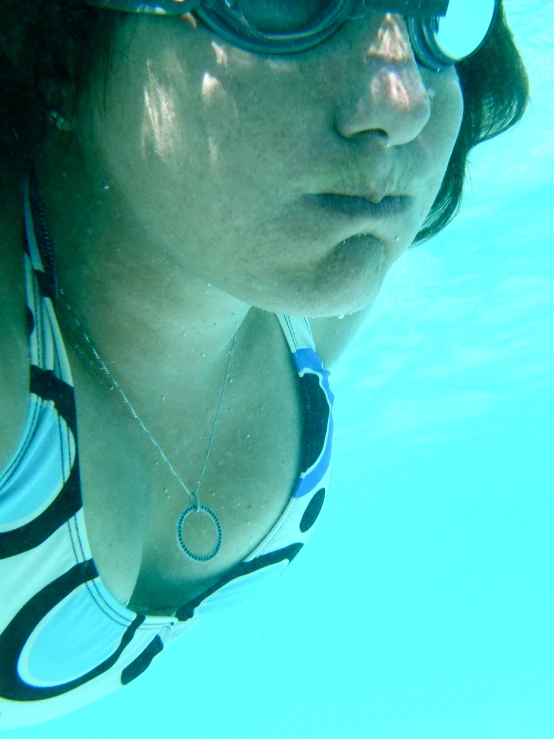 the young woman has on shades and is swimming underwater