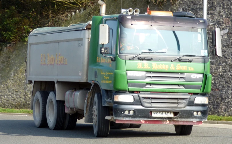 a green truck is driving on a road