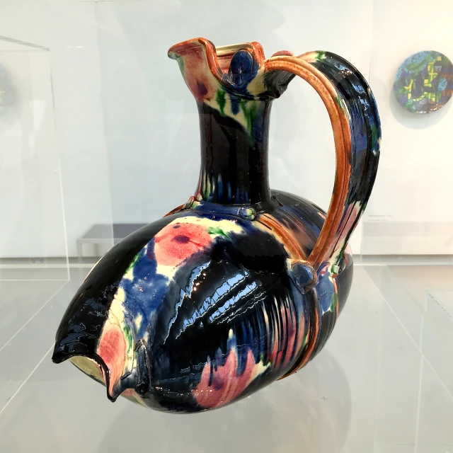 there is a colorful vase that is displayed in the glass case