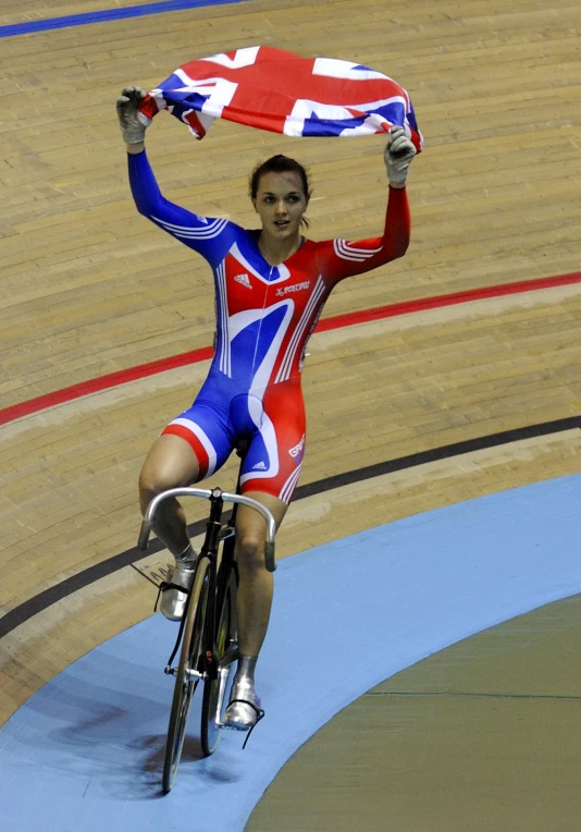 the british bicyclist rides her bike and holds up the union jack flag