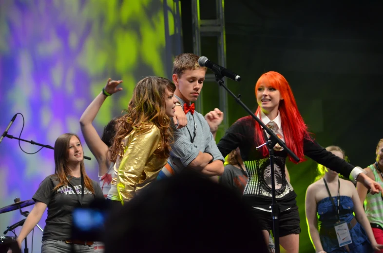 four people singing on stage and two have red hair