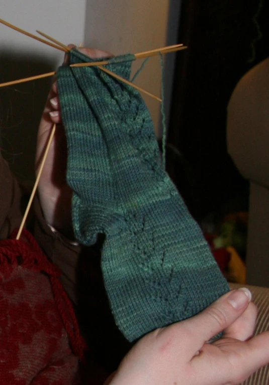 person holding up soing with yarn on a twig