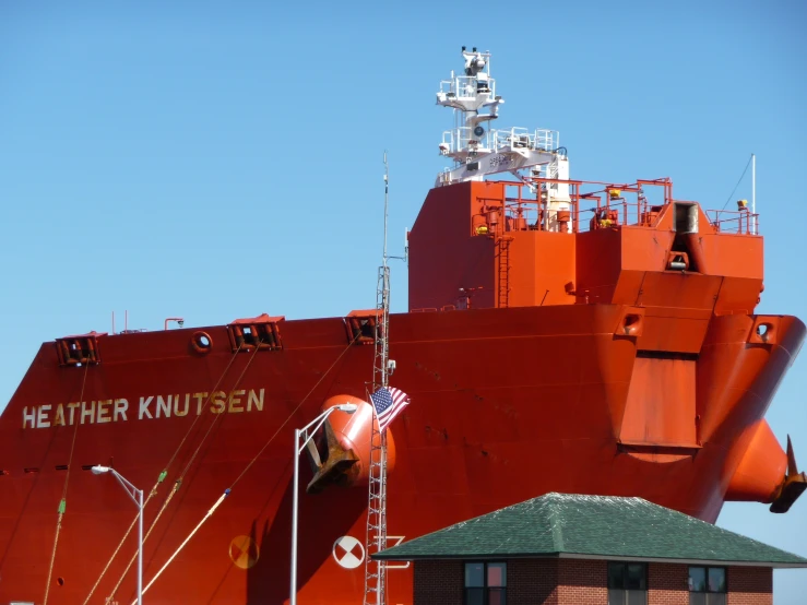 an orange ship sits in the water with other ships