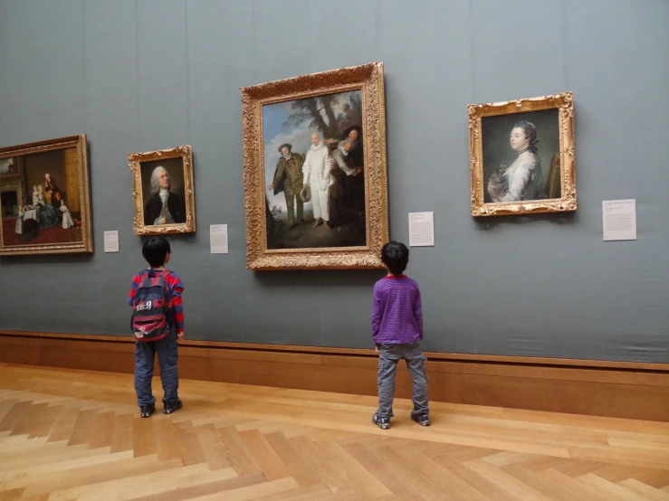 two children looking at a painting on display
