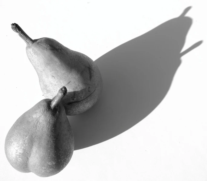 two pears on a white surface the only one has a shadow