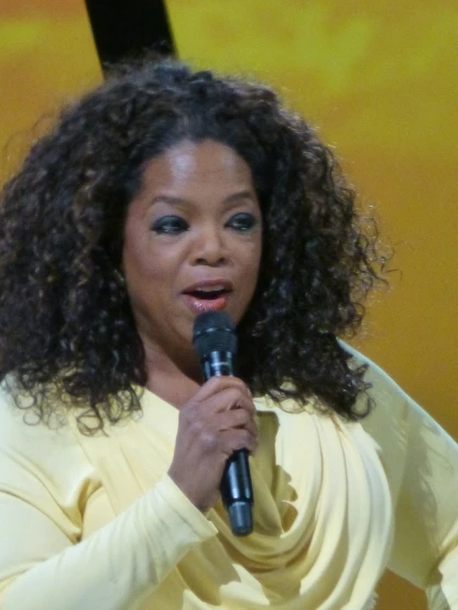 a woman wearing a yellow top and holding a microphone