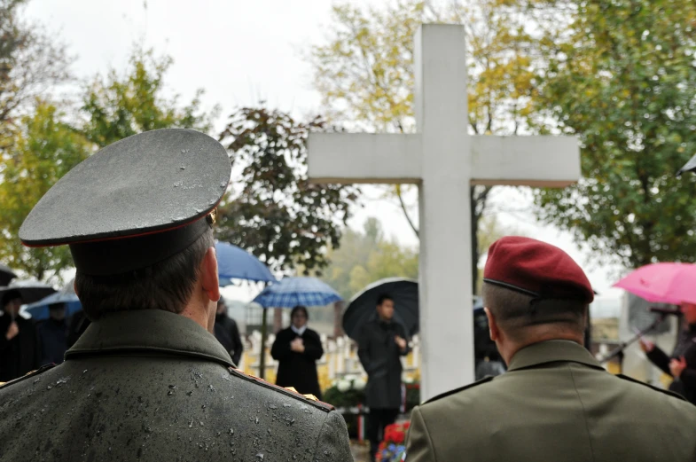 people in uniform are standing near a white cross