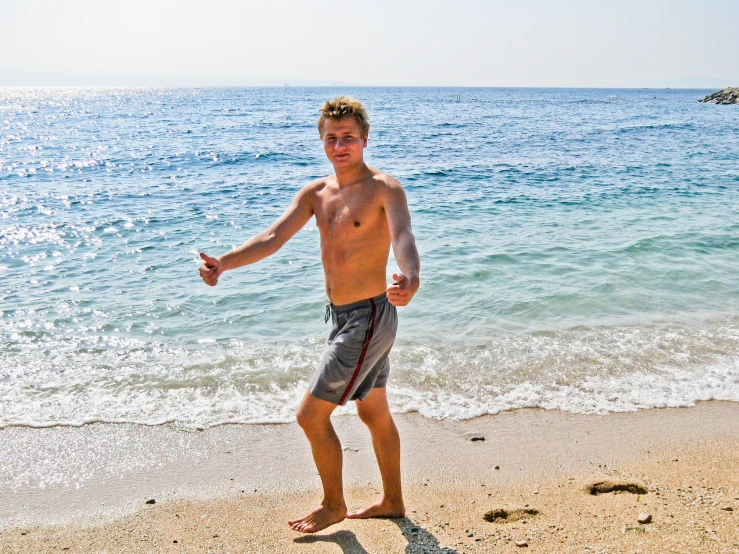 young man playing with frisbee on the beach near the ocean