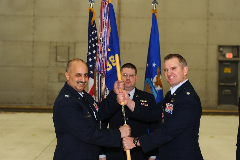 three men in uniforms holding up flags with poles