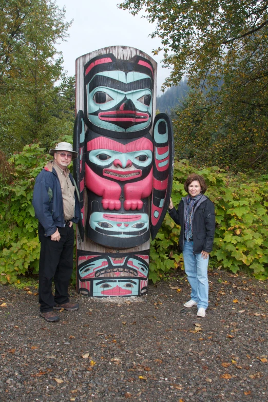 two people standing in front of a large wooden statue