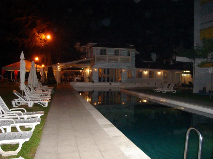 white lawn chairs along a swimming pool side