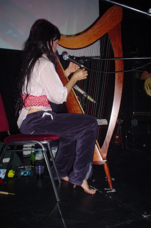 a woman sitting down and playing the harp