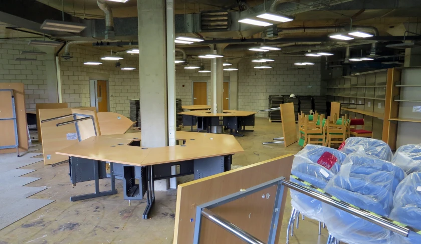 an empty office filled with wooden desks and plastic bags