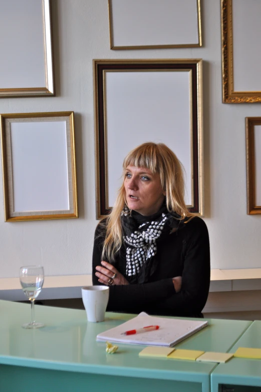 the woman is sitting at the table with a cup