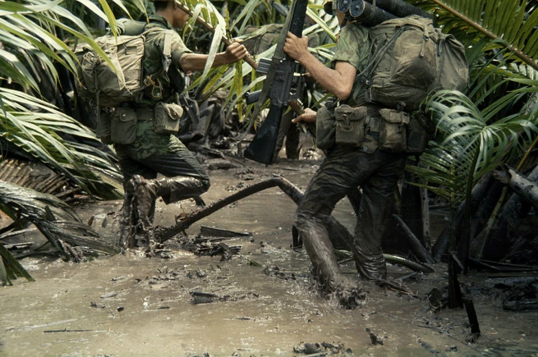 two soldiers standing near a bush in the jungle