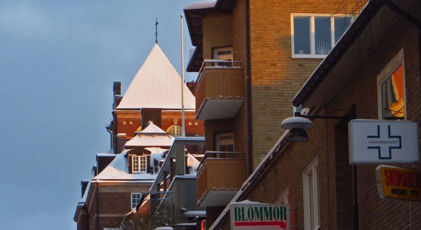 an upward view of the roof of several buildings with some snow on them