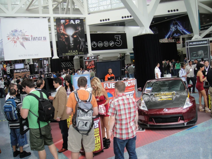 a crowd gathered together at the convention watching a car on display