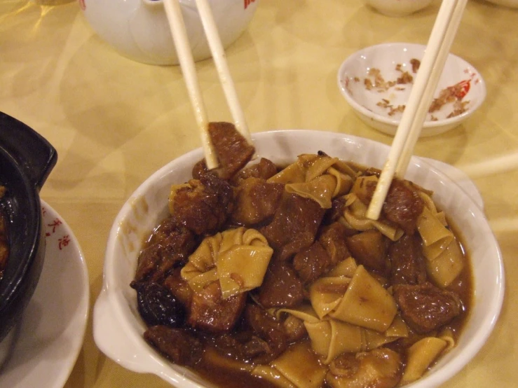 a bowl full of meat and noodles is on a table