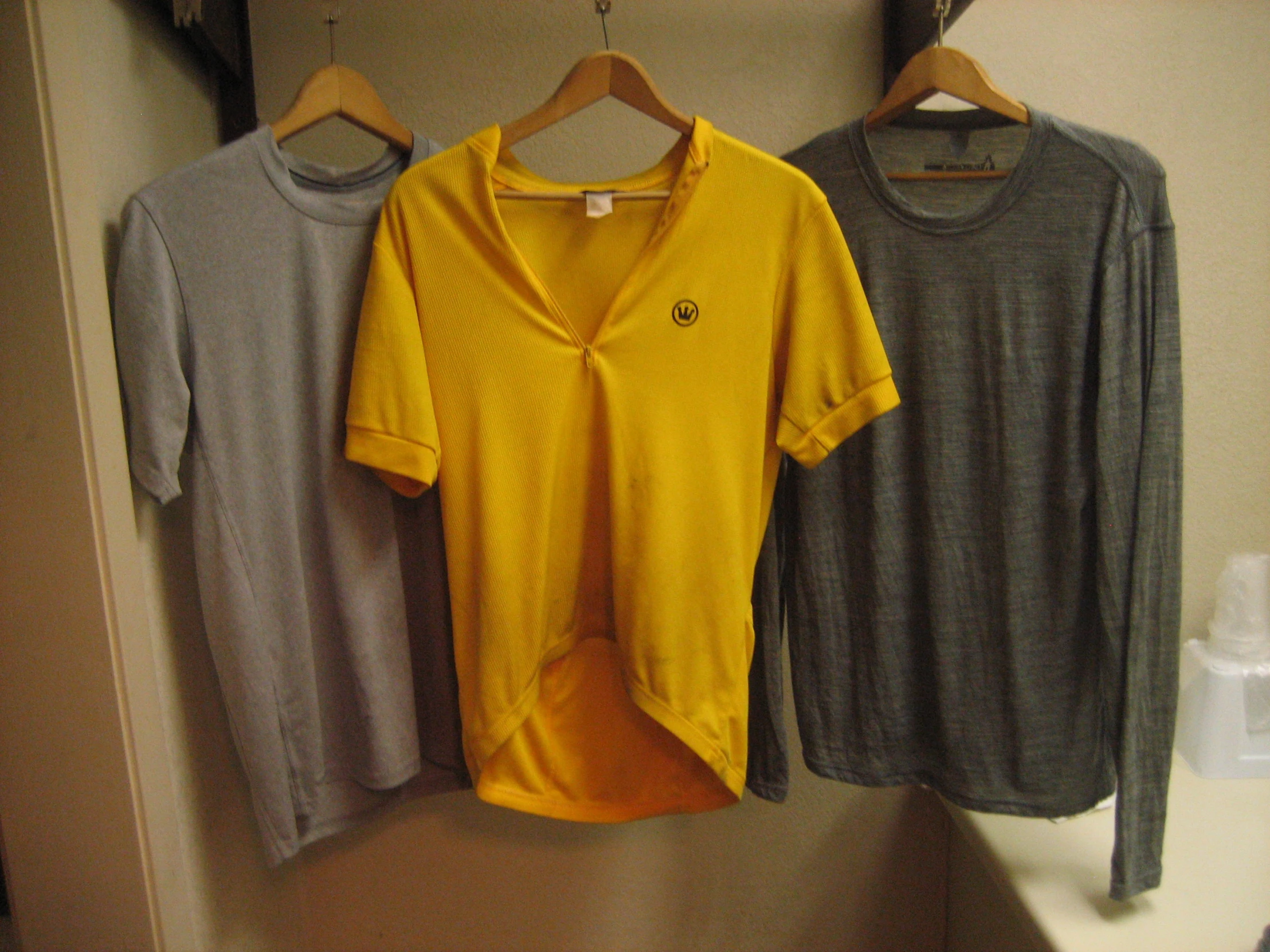 three t shirts hang on a clothes line in a closet
