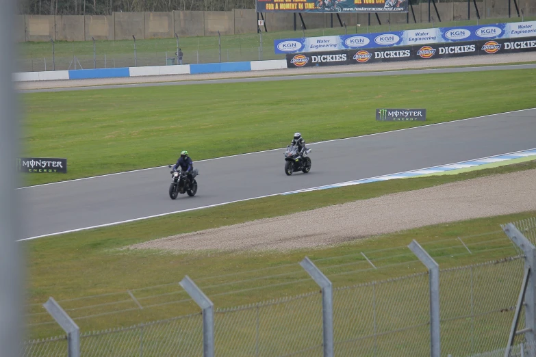 two people on motorcycles racing down a track