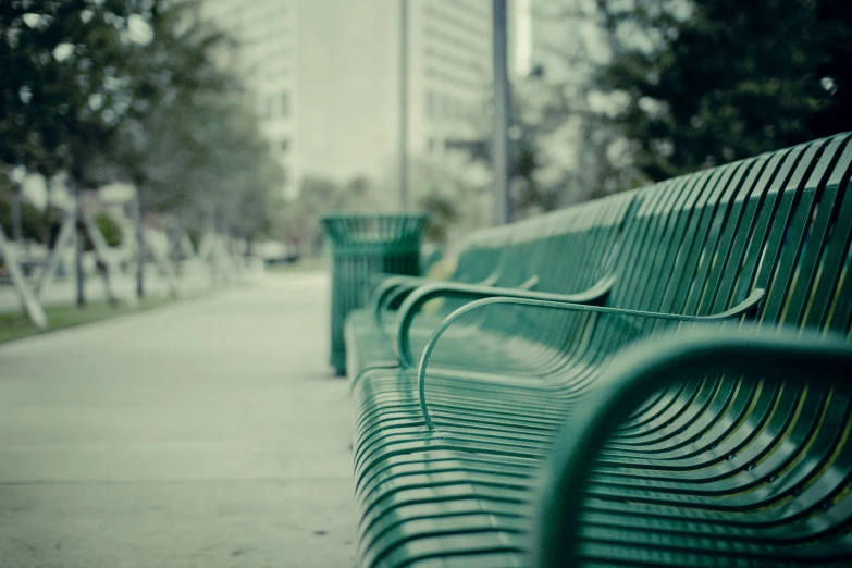 two empty park benches are lined up along a paved path