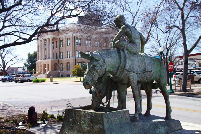 a statue of a man riding a horse by the side of the road